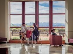 Students studying at table in front of large windows overlooking New York City skyline